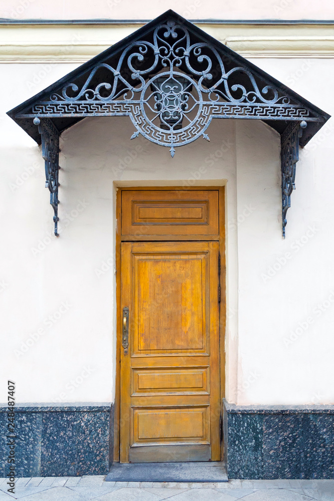 Φωτογραφία View on a porch with brown wooden door and forged decorative lattice on the pedi
