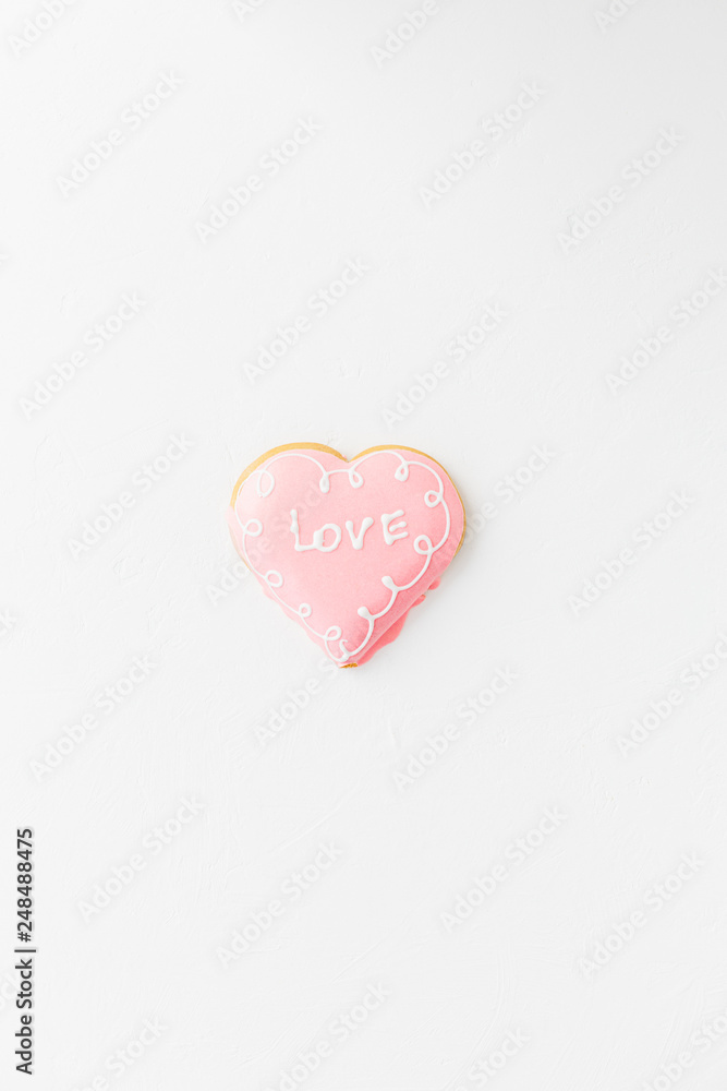 Heart shape cookie with love sign on white textured background