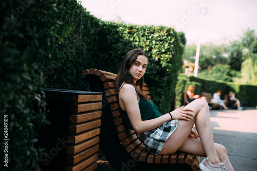 A girl in a black shirt and shorts in a park on a bench
