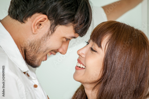 Young couple in love looking to each other. wife helping husband to get dress up in morning romantic moment