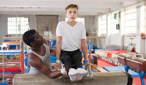 Adult African male coach helping teenage boy