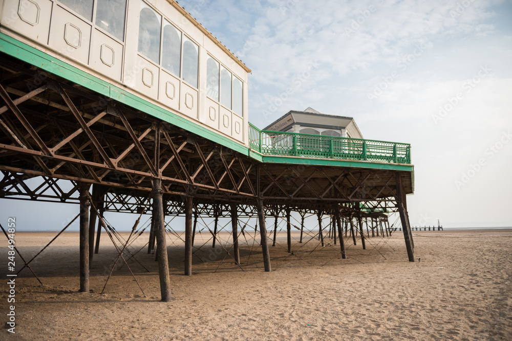 A beautiful old vintage steel iron victorian seaside pier structure shot from beneath, victorian architecture on the sandy beach, seaside landmark buildings.