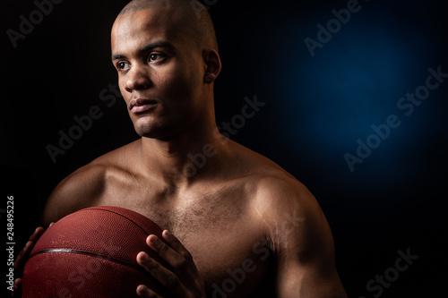 Studio portrait of Black basketball player holds a ball