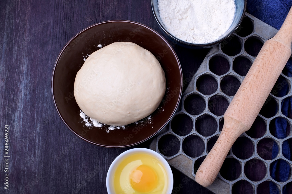 Dough and utensils for making dumplings against the dark background Dough and utensils for making dumplings against the dark background