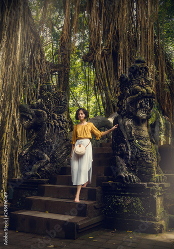 Girl in the Monkey Forest. Bali. Girl in a white dress on the nature. Traditional Balinese bag. Travel.