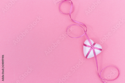  Love concept. White Heart and pink ribbon on pink paper background.