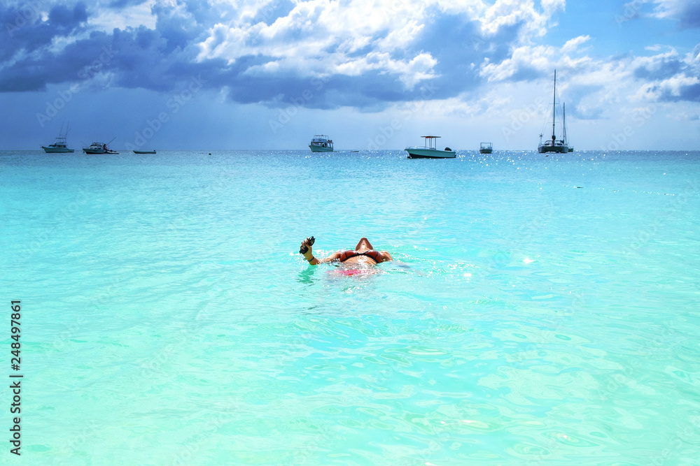 Girl in sunglasses in the water looks at the ocean and boats in the rays of the sun Zanzibar Island