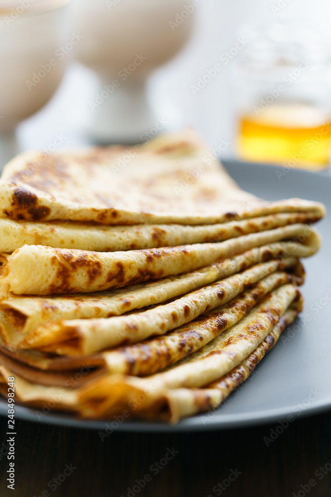 Crepes on a grey ceramic plate served with honey and 2 cups of tea. Dark wooden table, high resolution Crepes on a grey ceramic plate served with honey and 2 cups of tea. Dark wooden table, high resolution