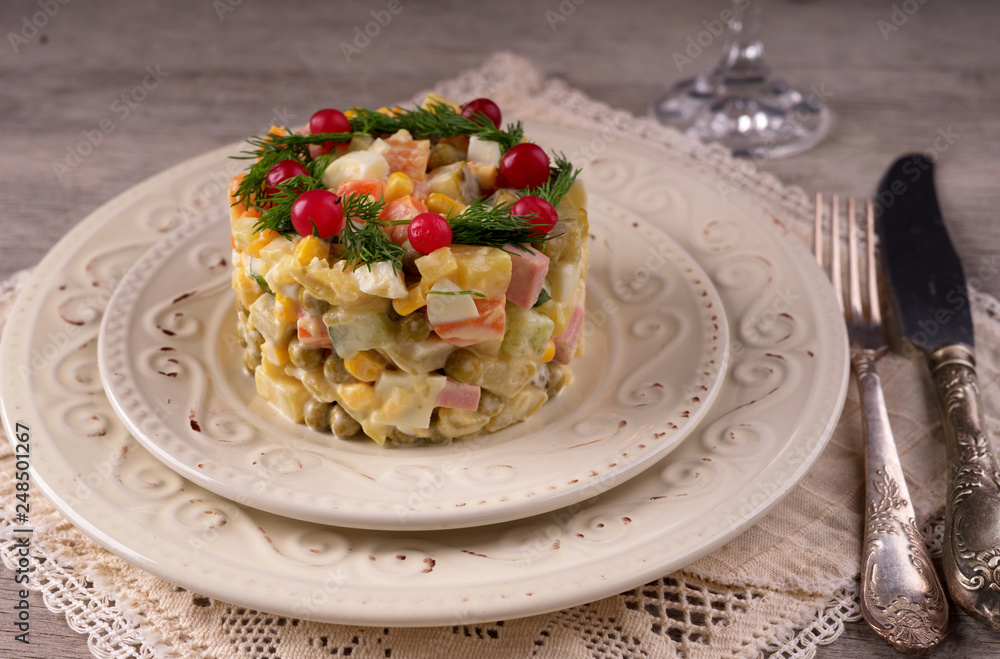 Russian salad on a white plate and cutlery on the table. Russian salad on a white plate and cutlery on the table.