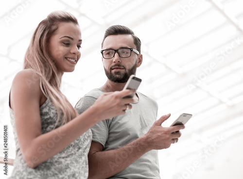 young couple looking at the screens of their smartphones