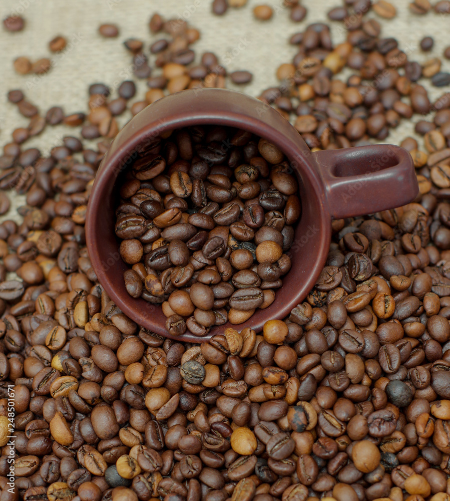Fototapeta premium A cup of coffee full of coffee beans. Coffee cup and coffee beans. Grain coffee on burlap.