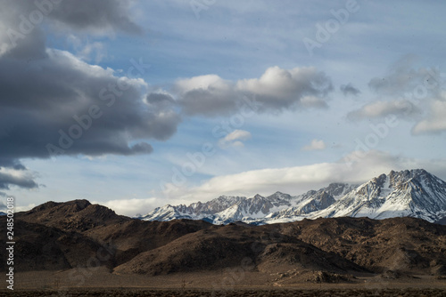snowy mountains brown desert hills clouds sky Eastern Sierras of California winter landscape