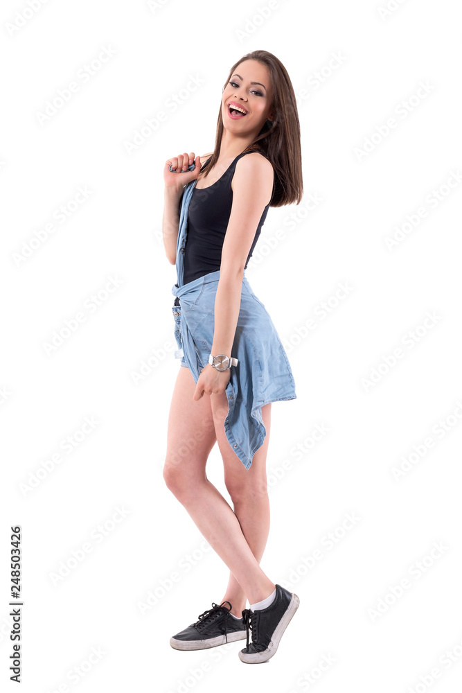 Excited young teenage girl in stylish casual clothes tying jeans