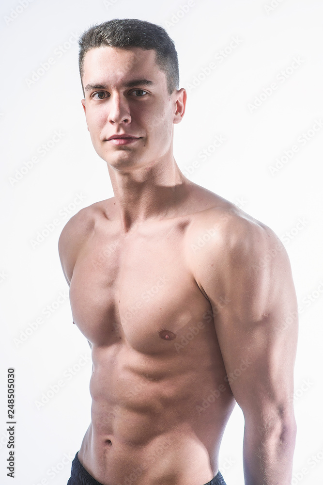 Beautiful young European athletic with bare torso, nice abs and muscles on white and gray background