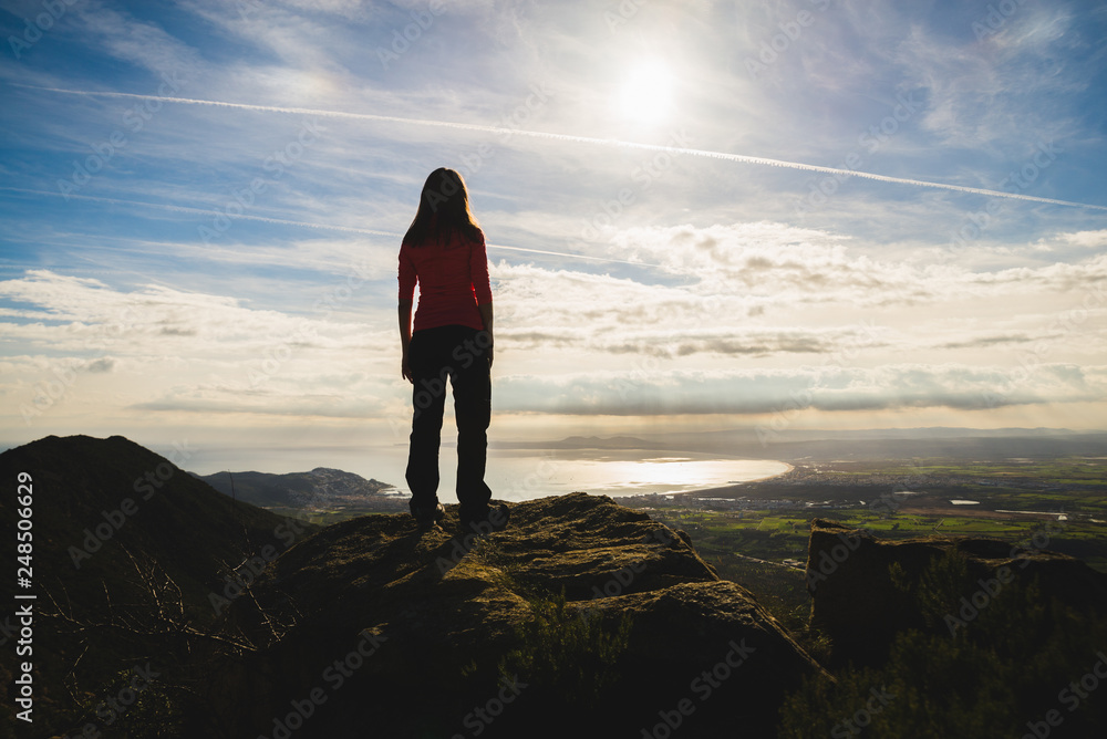 Girl on top of a cliff watching a beautiful landscape