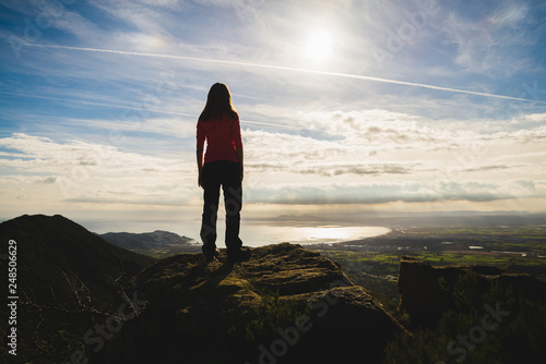 Girl on top of a cliff watching a beautiful landscape