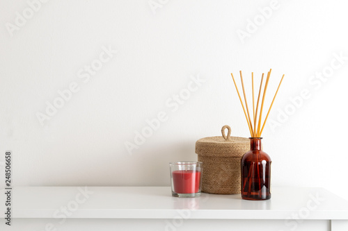 Scandinavian nordic hygge style, home interior - candle, scent aroma diffuser, small straw basket, white shelf