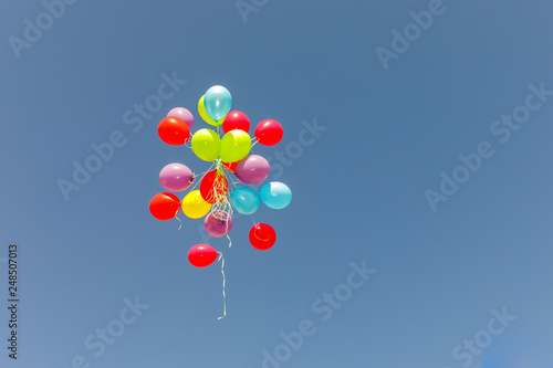 Big group multicolored balloons flying at sky