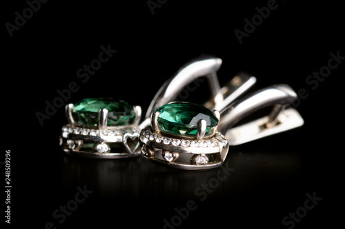 Jewelry silver earrings with green stone on a black background. Isolation