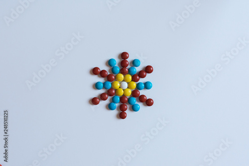 Colorful m m candy laid out in the shape of a floral mosaic isolated on white background. Decorative arnament