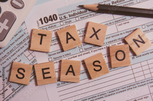 Tax season with wooden alphabet blocks, calculator, pencil on 1040 tax form background photo