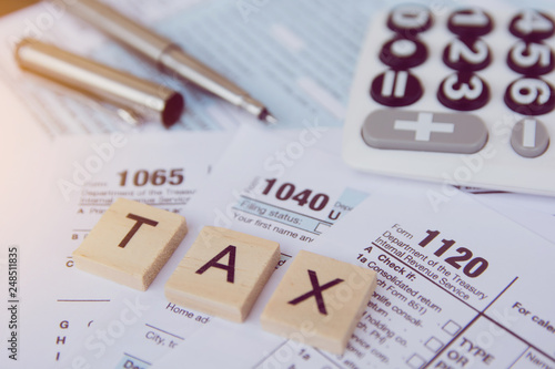 Tax season with wooden alphabet blocks, calculator, pen on 1040 tax form backgrounda photo