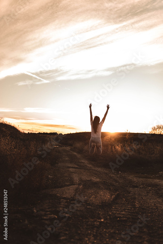 young woman jumping at sunset in the field