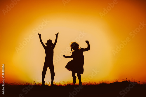 Silhouette of happy children boys and girls jumping and dancing in sunset sky evening time background as successful  happiness and careless concept