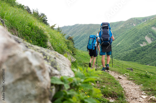 Trekking in mountains. Climbers with backpacks hiking in mountain trail