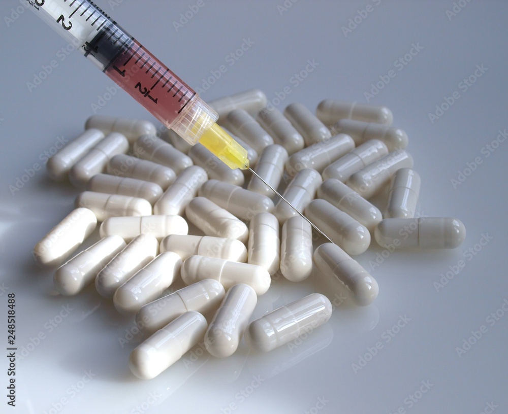 medicine: bunch of white capsules and syringe over white background medicine: bunch of white capsules and syringe over white background