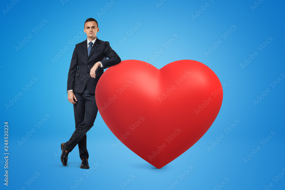 Businessman and big red heart model on blue background Businessman and big red heart model on blue background
