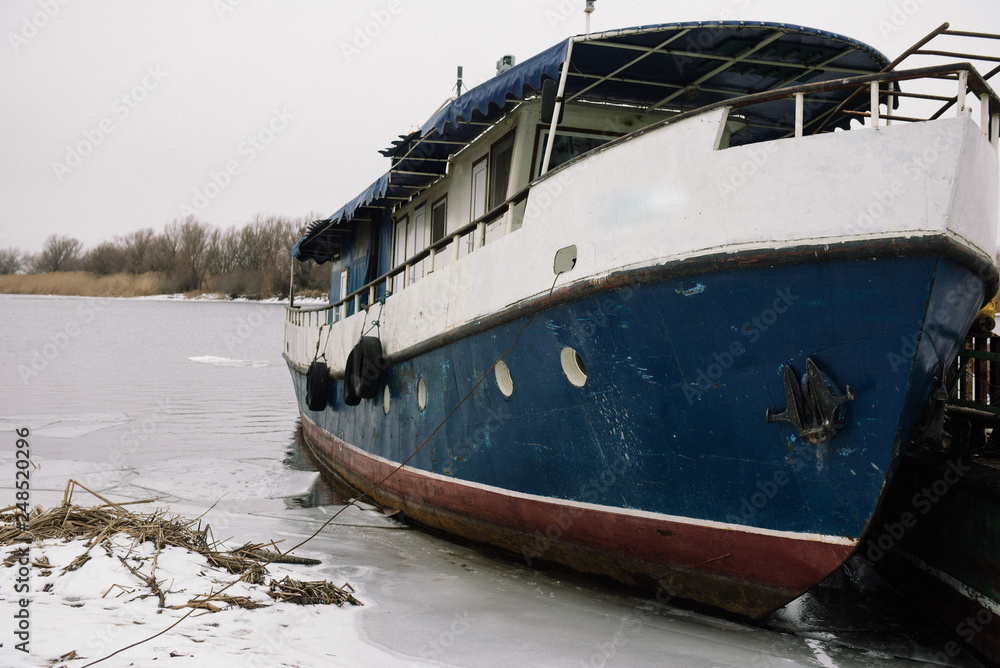 Fototapeta premium A small old ship is on the pier on the coast in winter