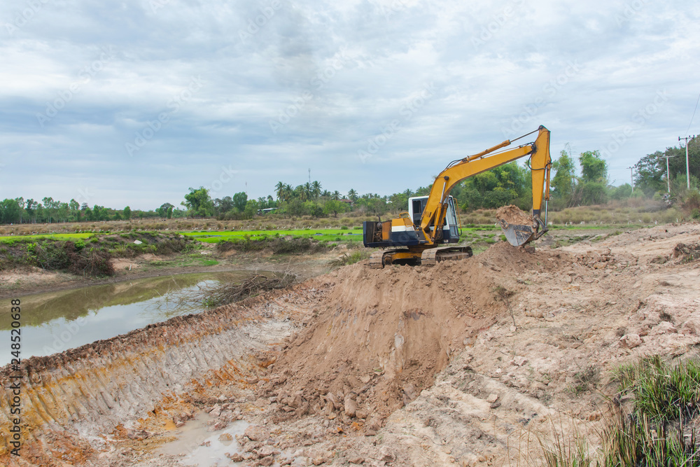 Obraz premium Yellow excavator machine working earth moving works at construction site