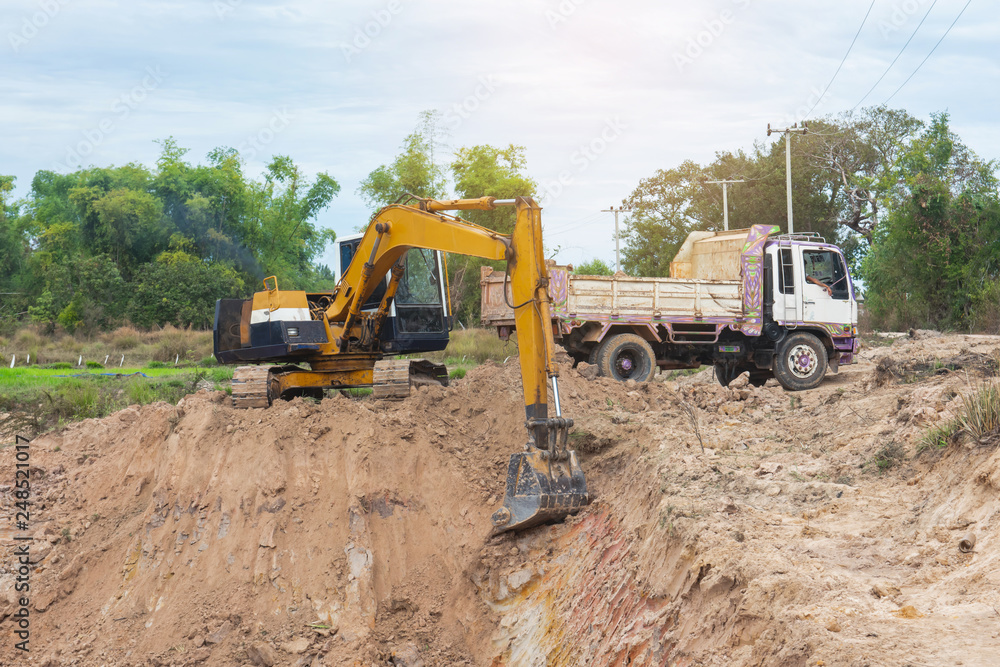 Yellow excavator machine loading soil into a dump truck at construction site Yellow excavator machine loading soil into a dump truck at construction site
