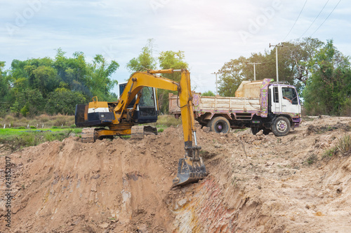 Yellow excavator machine loading soil into a dump truck at construction site