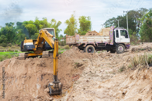 Yellow excavator machine loading soil into a dump truck at construction site