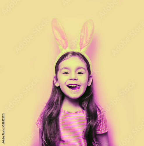Easter girl portrait. Cute little girl with bunny ears on pink background. Easter child portrait, funny emotions, surprise. Copyspace for text.