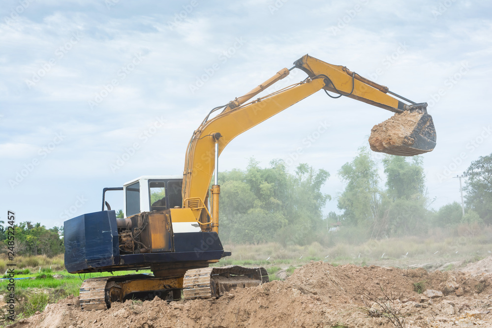 Yellow excavator machine working earth moving works at construction site Yellow excavator machine working earth moving works at construction site