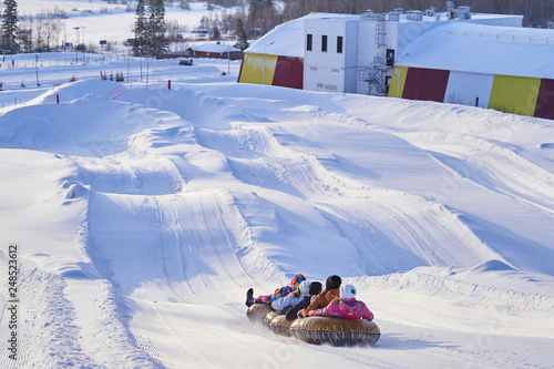 A group of friends riding tubing from a snowy mountain in winter