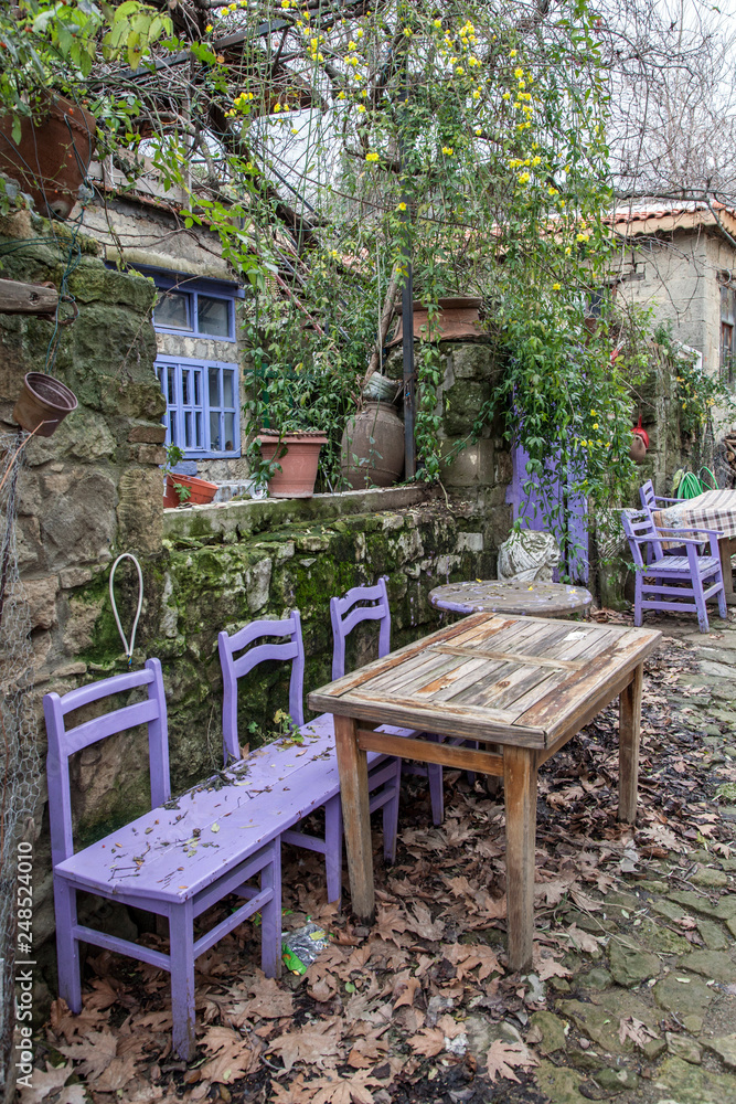 colorful chairs and tables in abandoned garden at autumn (adatepe village)