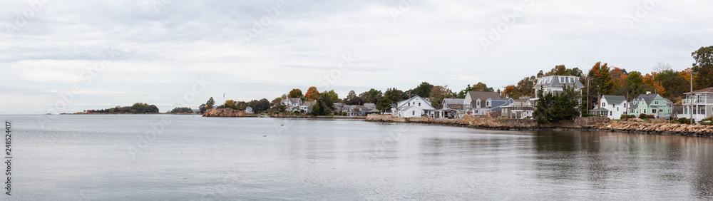 Panoramic view on residential homes on the Rocky Coast during a cloudy morning. Taken on the Atlantic Ocean in New Haven, Connecticut, United States. Panoramic view on residential homes on the Rocky Coast during a cloudy morning. Taken on the Atlantic Ocean in New Haven, Connecticut, United States.