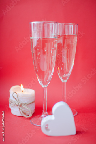 Two glasses with champagne on a red background. A date on valentines day