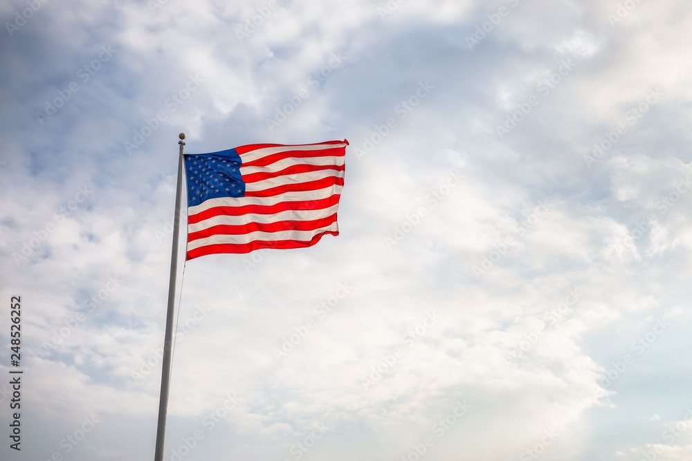 American Flag on the Cloudy background. - obrazy, fototapety, plakaty 