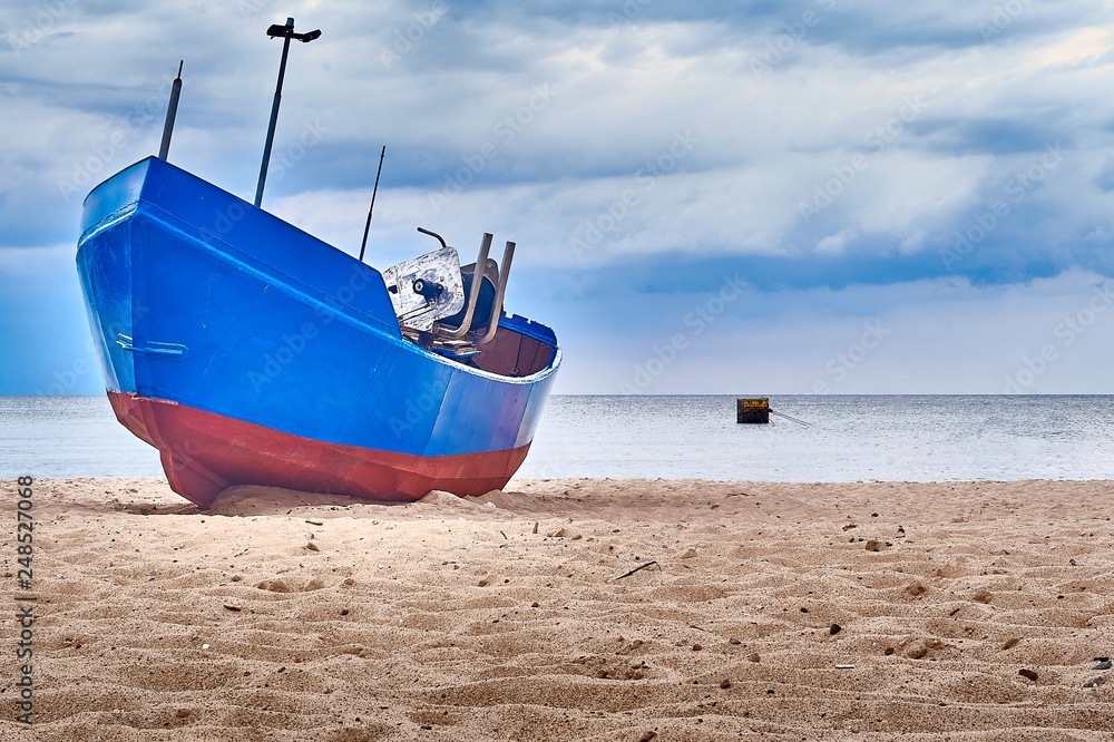 Blue fishing boat sitting on the beach of Rewal, Poland