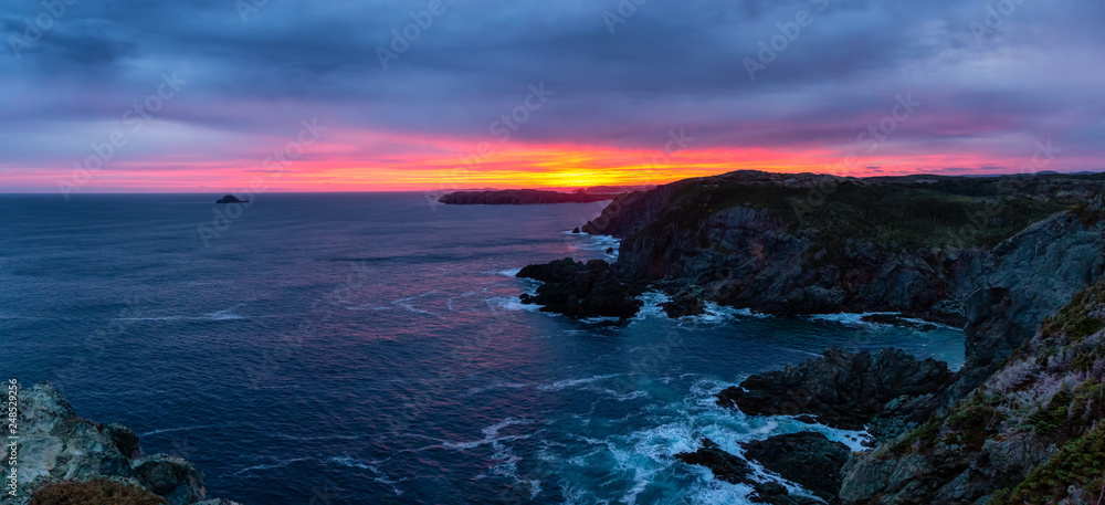 Striking panoramic seascape view on a rocky Atlantic Ocean Coast during a colorful sunrise. Taken at Crow Head, North Twillingate Island, Newfoundland and Labrador, Canada.