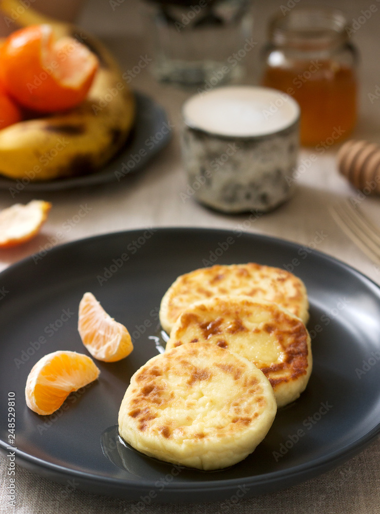 Vegetarian breakfast of quark pancakes with honey, fruit and coffee with milk. Rustic style. Vegetarian breakfast of quark pancakes with honey, fruit and coffee with milk. Rustic style.