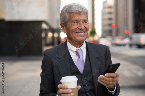 Senior businessman in city walking texting on cell phone © blvdone