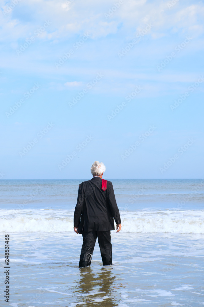 Business man walking into the beach Business man walking into the beach