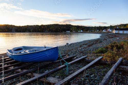 Wooden boat laying by the Atlantic Ocean Shore during a vibrant sunrise. Taken in Beachside  Newfoundland  Canada.