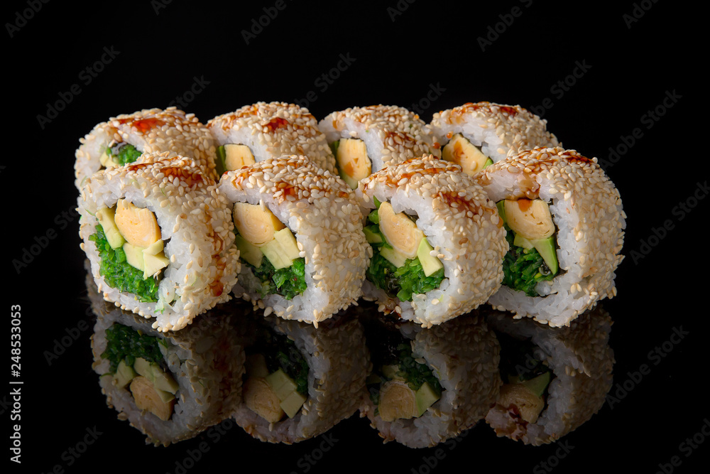 Sushi roll with egg omelet, avocado, chukka on black background. Sushi menu. Japanese food. Sushi roll with egg omelet, avocado, chukka on black background. Sushi menu. Japanese food.